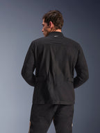 Alpinestars Dice Jacket, miejska kurtka motocyklowa, czarna, widok z tyłu prezentujący plisowane ramiona i regulowane patki w talii, estetyka kurtki polowej z małym białym logo na kołnierzu, ochronna odzież tekstylna do jazdy miejskiej