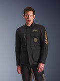 Alpinestars Dice Jacket, czarna kurtka motocyklowa, prezentowana przez modela, złote logo Alpinestars, liczne funkcjonalne kieszenie, okrągła naszywka ze spiralą, stylistyka miejskiej kurtki polowej