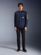 Alpinestars Dice Jacket, miejska kurtka motocyklowa, ciemnoniebieska i czarna, prezentowana na modelu z czarnymi spodniami i czarnymi butami, nowoczesny fason kurtki terenowej z wieloma kieszeniami, pionowy zamek na klatce piersiowej, białe logo Alpinestars na rękawach
