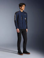 Kurtka Alpinestars Dice, ciemnoniebieska i czarna, nowoczesna kurtka motocyklowa w stylu field jacket, noszona przez modela z czarnymi spodniami i czarnymi wysokimi sneakersami, z licznymi kieszeniami użytkowymi, pionowym logo Alpinestars na rękawie i tkanymi naszywkami, współczesna odzież miejska na motocykl