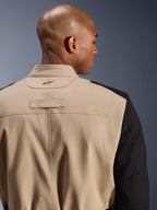 Alpinestars Dice Jacket, miejska kurtka motocyklowa, piaskowa i czarna, zbliżenie na detale kołnierza i ramienia z tyłu, z haftowanym logo, wytrzymała konstrukcja z diagonalnej polibawełny, miejski styl odzieży roboczej