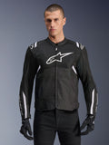 Alpinestars T-SPS Air V2 Jacket, tekstylna kurtka motocyklowa, czarna z białymi akcentami, duże białe logo na piersi, perforowana konstrukcja z siatki dla wentylacji, noszona z czarnymi spodniami i rękawicami
