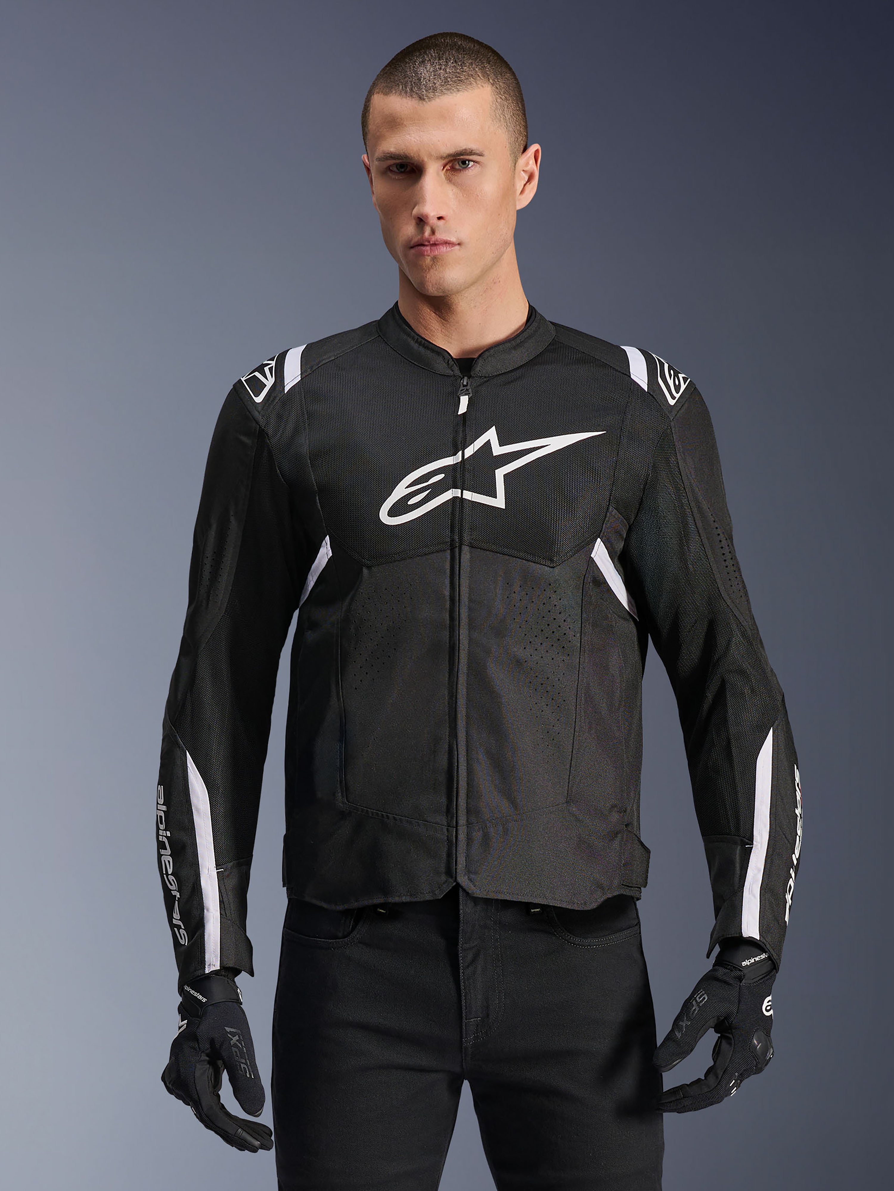 Alpinestars T-SPS Air V2 Jacket, Textile Motorcycle Jacket, Black with White Accents, large white chest logo, perforated mesh design for ventilation, worn with black pants and gloves
