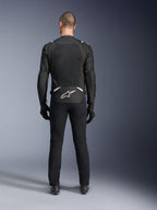 Alpinestars T-Sps Air V2 Jacket, widok z tyłu, czarno-biała tekstylna kurtka motocyklowa, duży panel z siatki na plecach zapewniający maksymalny przepływ powietrza, białe logo Astars w dolnej części pleców, zestawiona z czarnymi spodniami i rękawicami