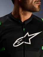 Zbliżenie na kurtkę Alpinestars T-SPS Air V2, czarno-zielona (Fluo Green), z oddychającymi panelami tech mesh, centralnym zamkiem i wyraźnym białym logo gwiazdy Alpinestars na klatce piersiowej, wyczynowa odzież motocyklowa