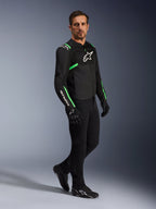 Męski model w kurtce Alpinestars T-SPS Air V2 w kolorze czarnym i Fluo Green, w zestawieniu z czarnymi spodniami i rękawicami motocyklowymi, sportowa kurtka tekstylna z panelami mesh i neonowymi akcentami, kompletny miejski strój motocyklowy