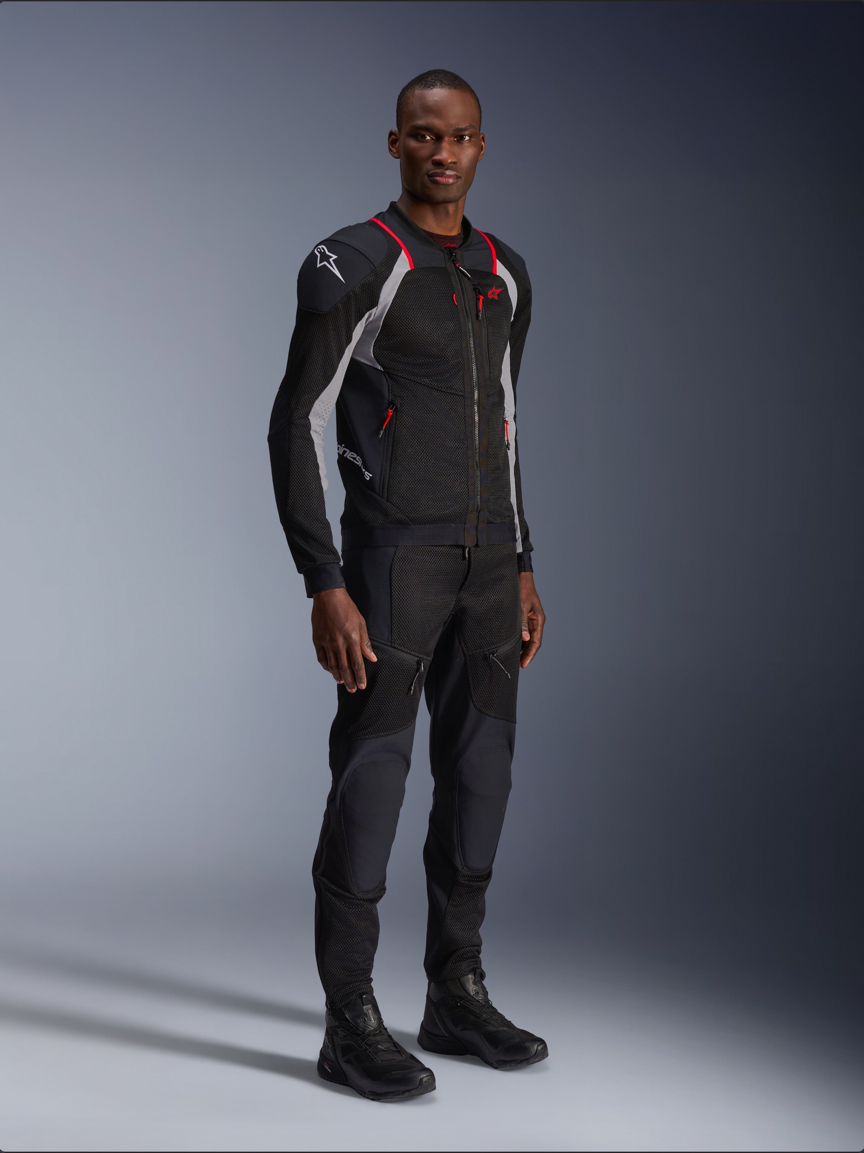 Kurtka Alpinestars Troop-Air Pro, Black Ash Gray i Bright Red, techniczna kurtka motocyklowa z siatki, z czerwonymi akcentami i białym logo na ramieniu, prezentowana z pasującymi czarnymi spodniami i butami, nowoczesna miejska odzież motocyklowa