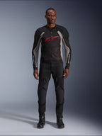 Męski model w kurtce Alpinestars Troop-Air w kolorze Black Ash Gray i Bright Red, techniczna siatkowa kurtka motocyklowa z wyraźnym czerwonym logo na klatce piersiowej, czarne spodnie i buty motocyklowe, miejska odzież motocyklowa