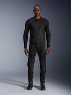 Męski model w kurtce Alpinestars Troop-Air Jacket w kolorze Black Black, lekka siatkowa kurtka motocyklowa, połączona z dopasowanymi czarnymi spodniami i butami motocyklowymi, techniczna konstrukcja z siatki 2D zapewniająca doskonały przepływ powietrza.