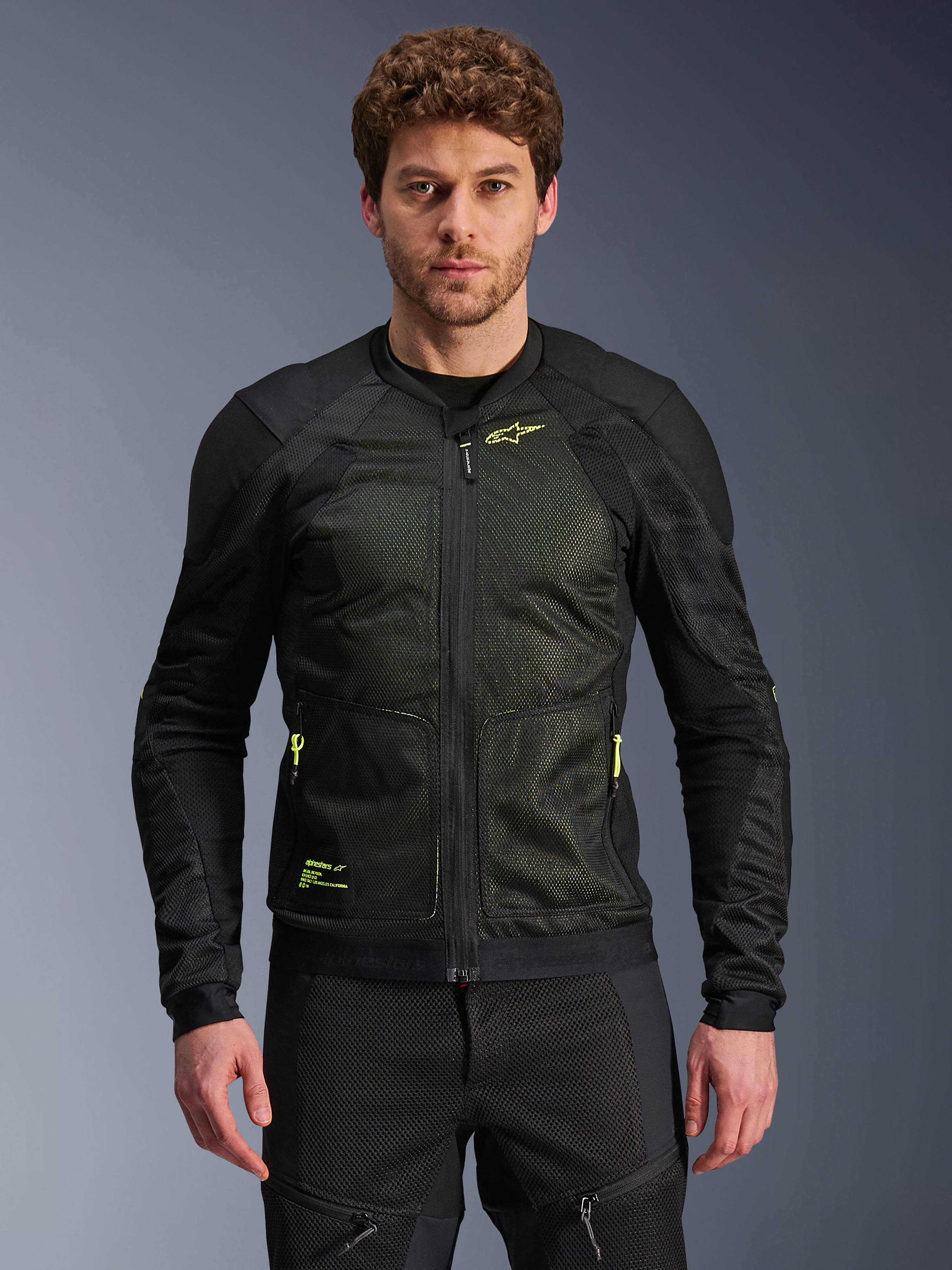 Alpinestars Troop-Air Jacket, czarna i żółta fluo, prezentowana na modelu, lekka konstrukcja z siatki mesh, neonowożółte zamki i branding, techniczna wentylowana kurtka motocyklowa do jazdy miejskiej.