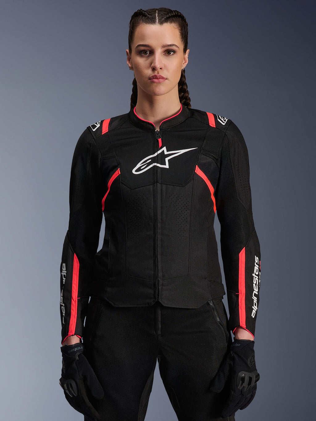 Alpinestars Woman Stella T-Sps Air V2 Jacket, czarna z różowymi akcentami (Diva Pink), tekstylna kurtka motocyklowa z oddychającymi panelami z siatki, białe logo Alpinestars na klatce piersiowej, prezentowana na modelce w czarnych spodniach motocyklowych i rękawicach