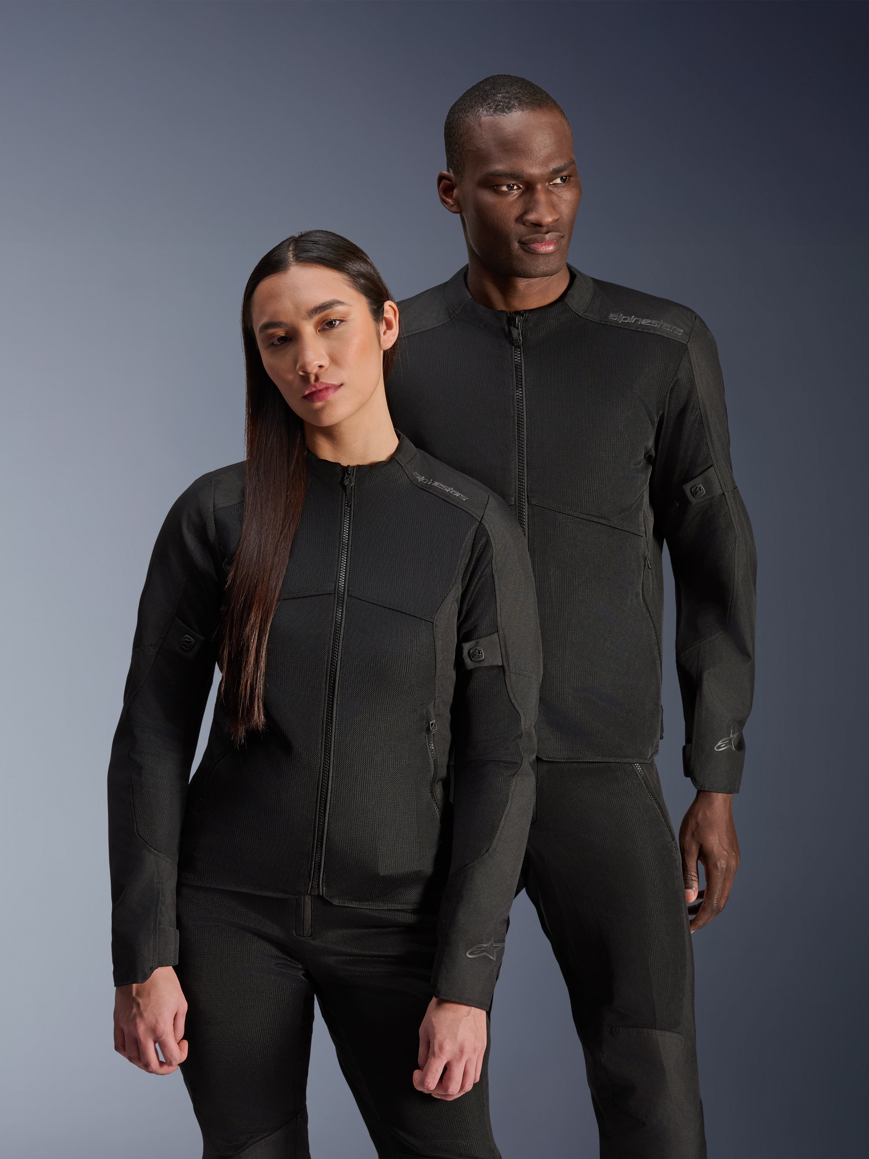 Kurtka Alpinestars Stella C-1 Air, czarna, noszona przez modela i modelkę, techniczna konstrukcja z siatki zapewniająca przepływ powietrza, odblaskowe logo, nowoczesna miejska odzież motocyklowa