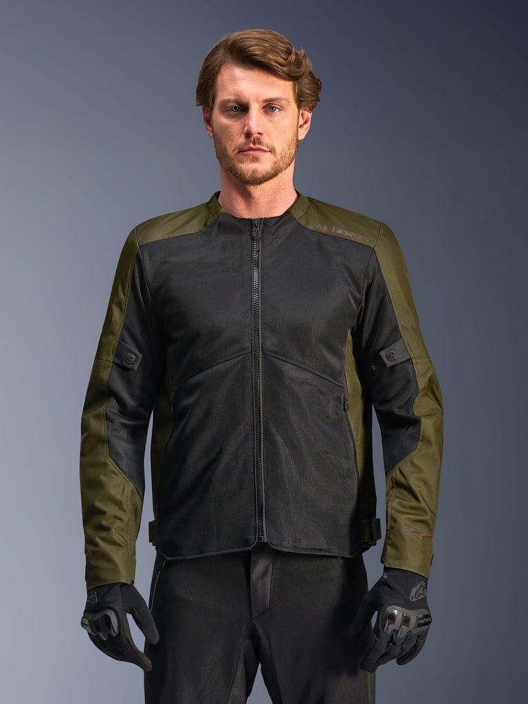 Alpinestars C-1 Air Jacket, męska kurtka motocyklowa, khaki i czarna, z dużymi panelami z siatki technicznej dla maksymalnego przepływu powietrza, noszona przez modela z czarnymi spodniami i rękawicami, nowoczesny miejski design do codziennych dojazdów.