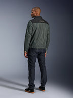 Kurtka Alpinestars Ignite Air w kolorze Urban Gray Black Blue, widok z tyłu na modelu, siatkowy korpus z czarnym karczkiem i białym napisem, prążkowane mankiety, w zestawieniu z ciemnymi jeansami i czarnymi sneakersami, miejska odzież motocyklowa lifestyle