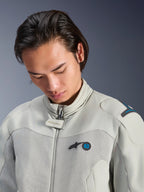 Męski model w kurtce Alpinestars Circal-1 Air Jacket w kolorze Metal Gray z akcentami Methyl Blue, zbliżenie podkreślające kołnierz, siateczkowe panele na klatce piersiowej i minimalistyczne logo, zrównoważona miejska odzież motocyklowa.