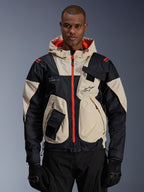 Alpinestars Mogress Air Jacket, miejska kurtka motocyklowa, beżowo-czarna z jaskrawopomarańczowymi zamkami i podszewką kaptura, fason z kapturem i kieszeniami użytkowymi, logo na piersi, noszona z czarnymi rękawicami