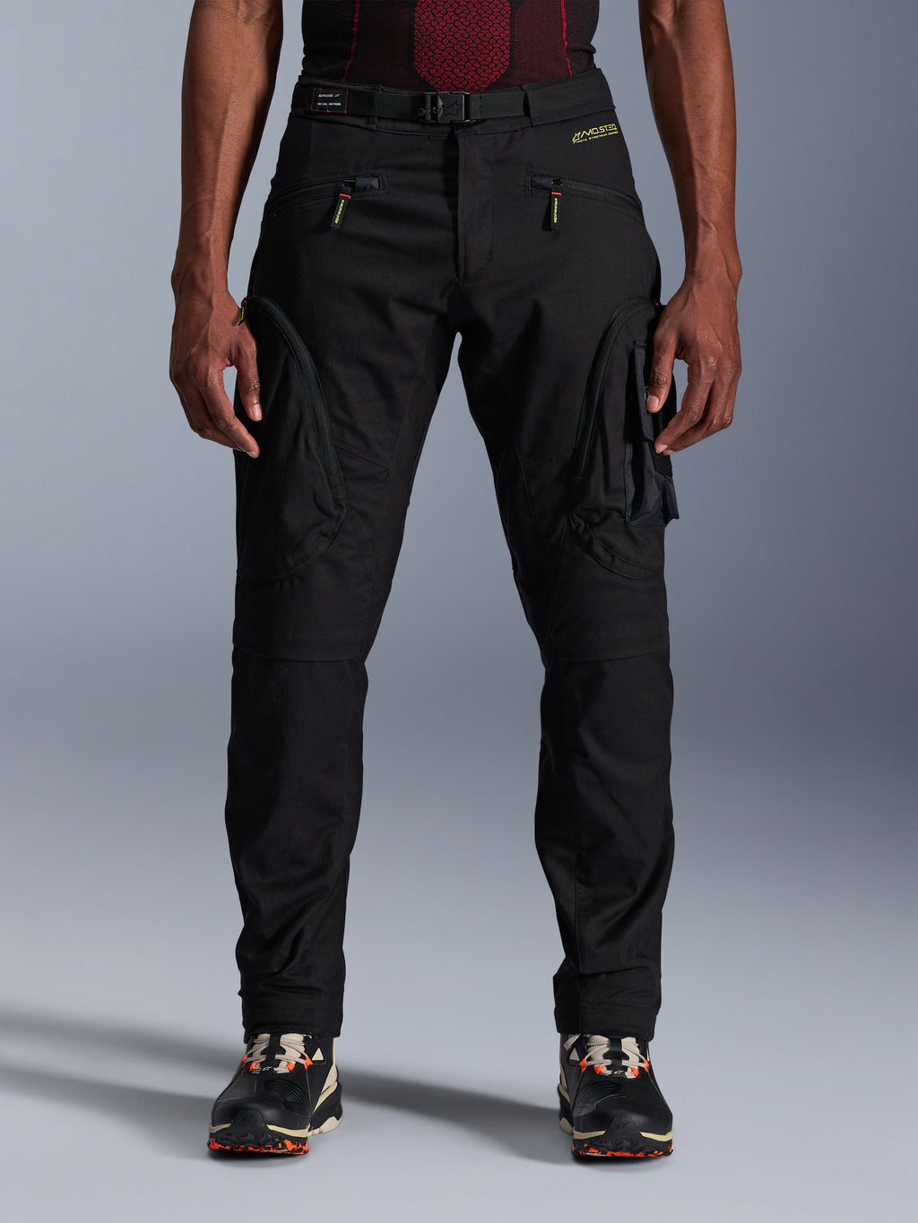 Alpinestars Acteon Pants, czarne miejskie spodnie motocyklowe, krój regular fit ze zwężanymi nogawkami, boczne kieszenie cargo z odwróconymi zamkami błyskawicznymi, zintegrowany pasek i żółte logo, ochronna odzież tekstylna