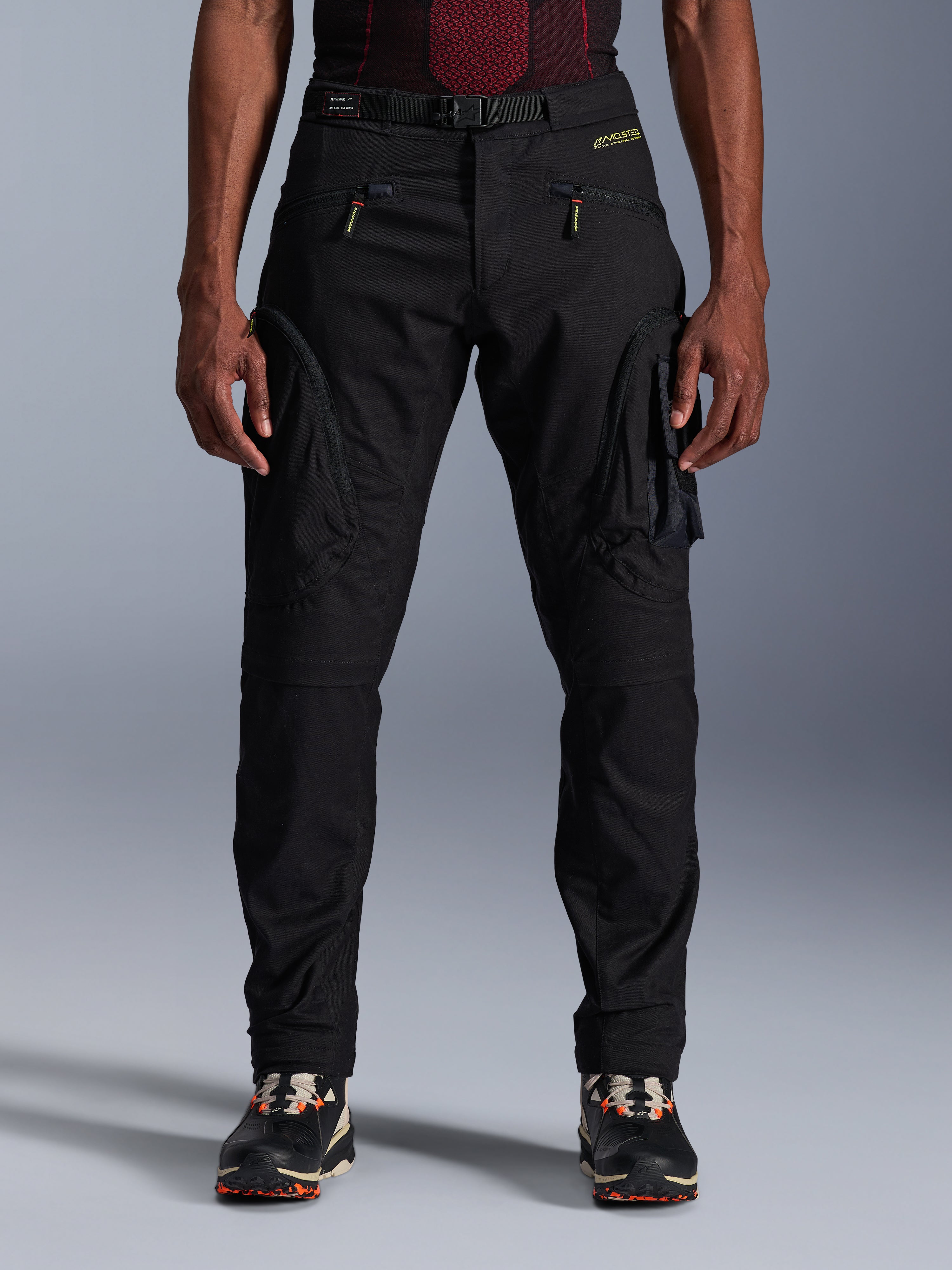 Alpinestars Acteon Pants, czarne miejskie spodnie motocyklowe, krój regular fit ze zwężanymi nogawkami, boczne kieszenie cargo z odwróconymi zamkami błyskawicznymi, zintegrowany pasek i żółte logo, ochronna odzież tekstylna
