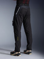 Spodnie Alpinestars Acteon, czarne spodnie motocyklowe, widok z tyłu i z boku ukazujący nowoczesny zwężany krój, boczna kieszeń cargo z logo, pionowe białe oznaczenie Alpinestars na górnej części uda, żółty napis „Alpinestars Protects” na dole nogawki, nowoczesna miejska odzież motocyklowa