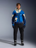 Kurtka Alpinestars Mogress Air, miejska kurtka motocyklowa Blue Almond, noszona z czarnymi spodniami i butami, o technicznym designie w niebieskie i kremowe bloki kolorystyczne, z funkcjonalnymi kieszeniami i kapturem, nowoczesna odzież motocyklowa inspirowana stylem streetwear