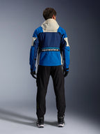Kurtka Alpinestars Mogress Air w kolorze Blue Almond, widok od tyłu motocyklisty w kurtce motocyklowej, granatowe i jasnoniebieskie panele z kapturem w kolorze złamanej bieli, wyraźne logo Alpinestars w dolnej części pleców, nowoczesny miejski styl odzieży motocyklowej.