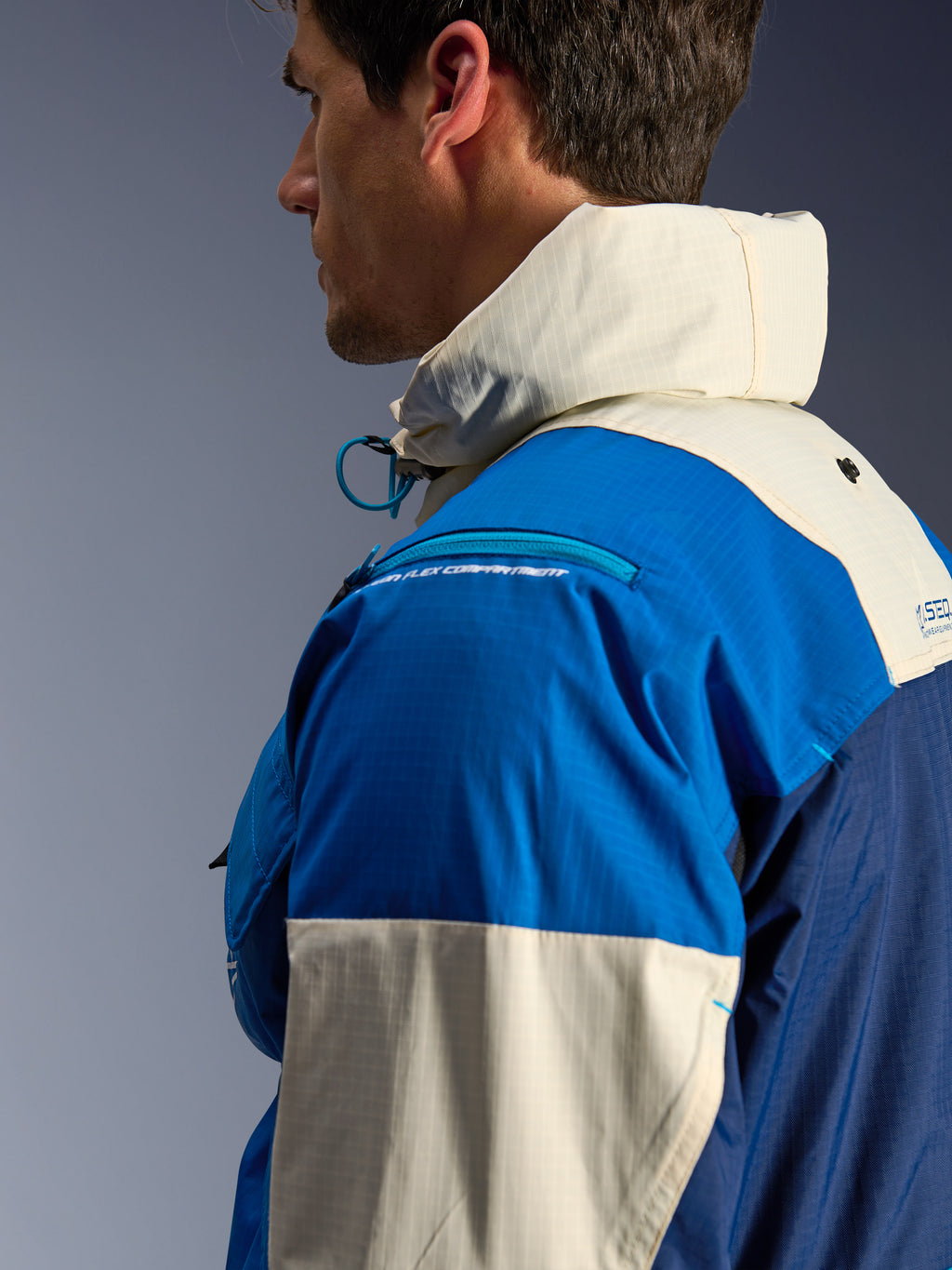 Kurtka Alpinestars Mogress Air w kolorze Blue Almond, zbliżenie z boku, materiał ripstop z nylonu z recyklingu, zapinana na zamek komora na ochraniacz ramienia, wysoki kołnierz ze zintegrowanym kapturem, współczesna miejska odzież motocyklowa streetwear