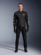 Model w kurtce Alpinestars T-Dyno Air, czarna, lekka motocyklowa kurtka tekstylna z oddychającą siatką 3D, białe logo gwiazdy na rękawach, zestawiona z czarnymi spodniami, rękawicami i butami, widok z przodu