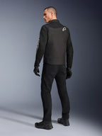 Alpinestars T-Dyno Air Jacket, czarna, widok od tyłu modelu w oddychającej tekstylnej kurtce motocyklowej, z białym logo Alpinestars na ramieniu, w zestawie z czarnymi spodniami i rękawicami, miejski styl jazdy