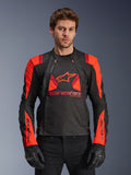 Alpinestars T-Stunt Air Jacket, tekstylna kurtka motocyklowa, czarna, jaskrawoczerwona i ciemnoczerwona, z dużym logo gwiazdy i panelami z siatki zapewniającymi przepływ powietrza, noszona przez modela w czarnych rękawicach