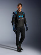 Męski model w kurtce Alpinestars T-Stunt Air, kolor czarny, granatowy i błękitny (Blithe Blue), z widocznymi panelami z siatki dla lepszego przepływu powietrza, w zestawieniu z czarnymi spodniami i rękawicami motocyklowymi, sportowa kurtka motocyklowa do letniej jazdy szosowej.