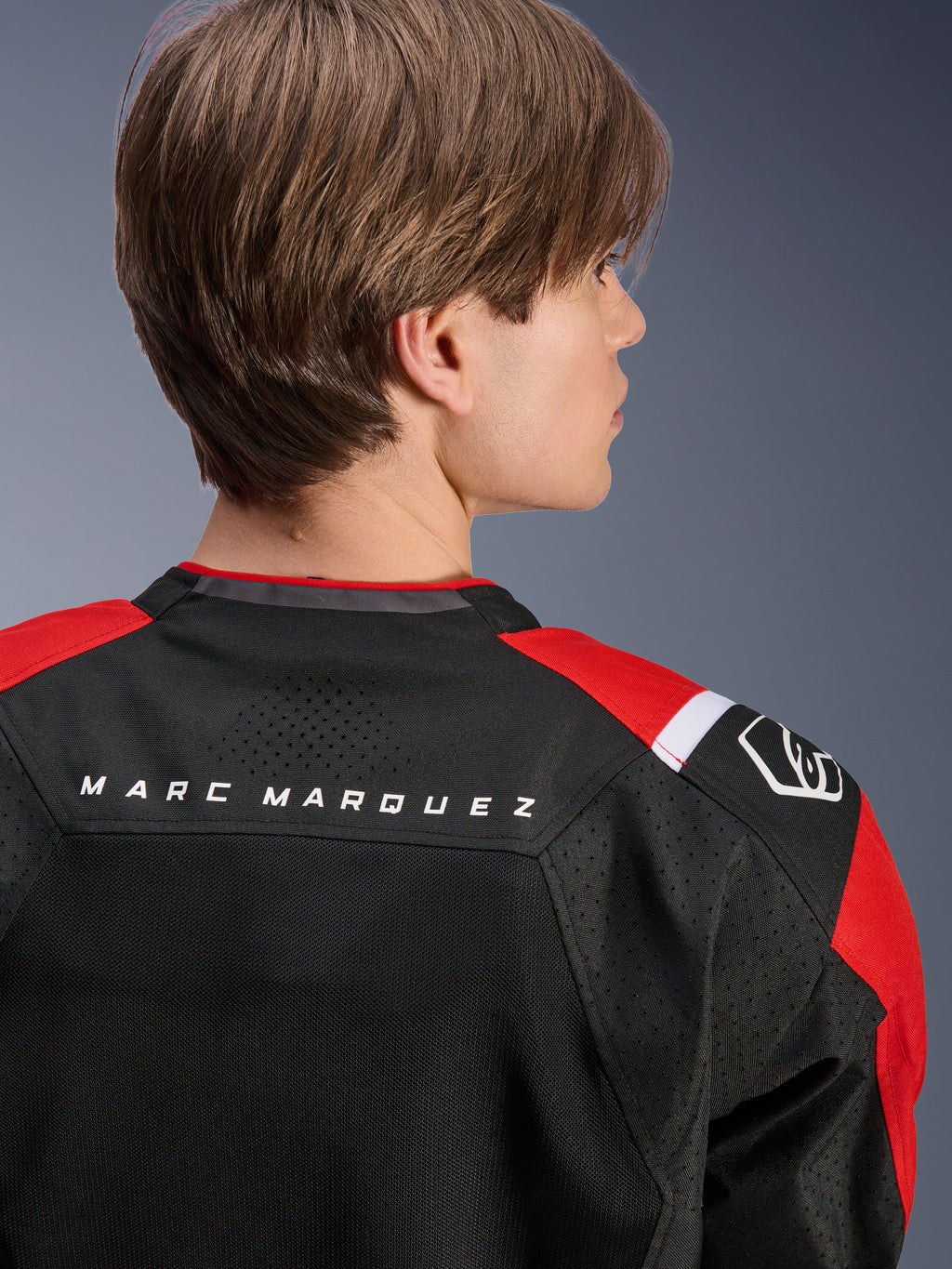 Alpinestars MM93 T-SPS Air V2 Jacket, rear view of the upper back and shoulders, Black with Bright Red and White details, 'MARC MARQUEZ' text across the yoke, featuring technical mesh panels and shoulder logo, urban sport motorcycle apparel