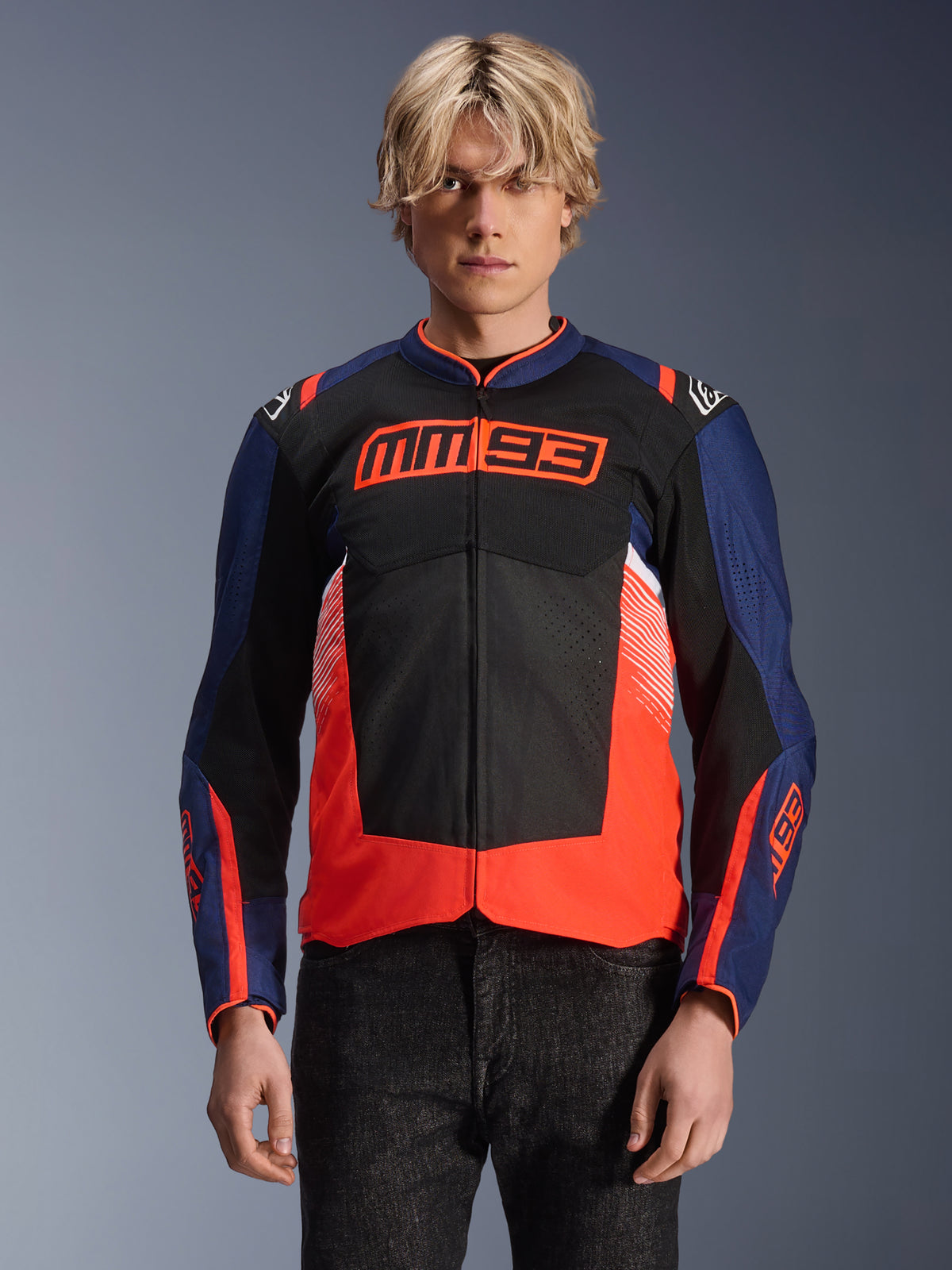 Alpinestars MM93 T-SPS Air V2 Jacket, tekstylna kurtka motocyklowa, granatowa, czarna i jaskrawoczerwona, noszona przez osobę, z wyraźnym logo MM93 na klatce piersiowej, panele z siatki dla wentylacji, nowoczesny design z blokami kolorów