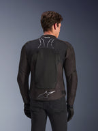 Kurtka Alpinestars SMX Air w kolorze Black Anthracite, widok z tyłu na modelu, duży panel z siatki technicznej na plecach zapewniający wentylację, oznaczenie Tech-Air Ready na kołnierzu, srebrne logo Astar na dole pleców, czarne rękawice i spodnie motocyklowe