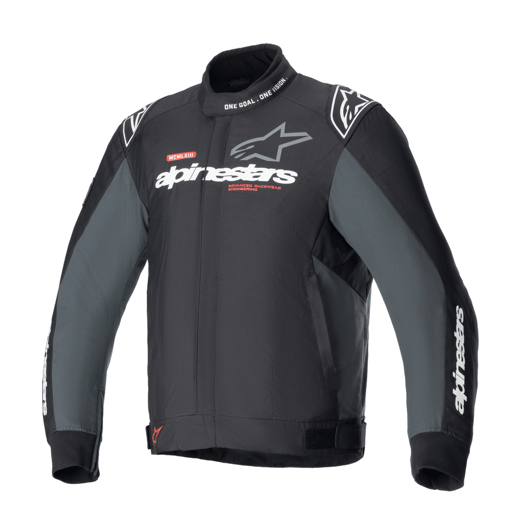 Alpinestars Monza Sport Jacket, tekstylna kurtka motocyklowa w kolorze czarnym i szarym, wysoki kołnierz z napisem „ONE GOAL. ONE VISION.”, białe i szare logo Alpinestars na piersi, logo gwiazdy na ramionach, czerwone akcenty graficzne, regulowane paski w talii, smukły design techniczny