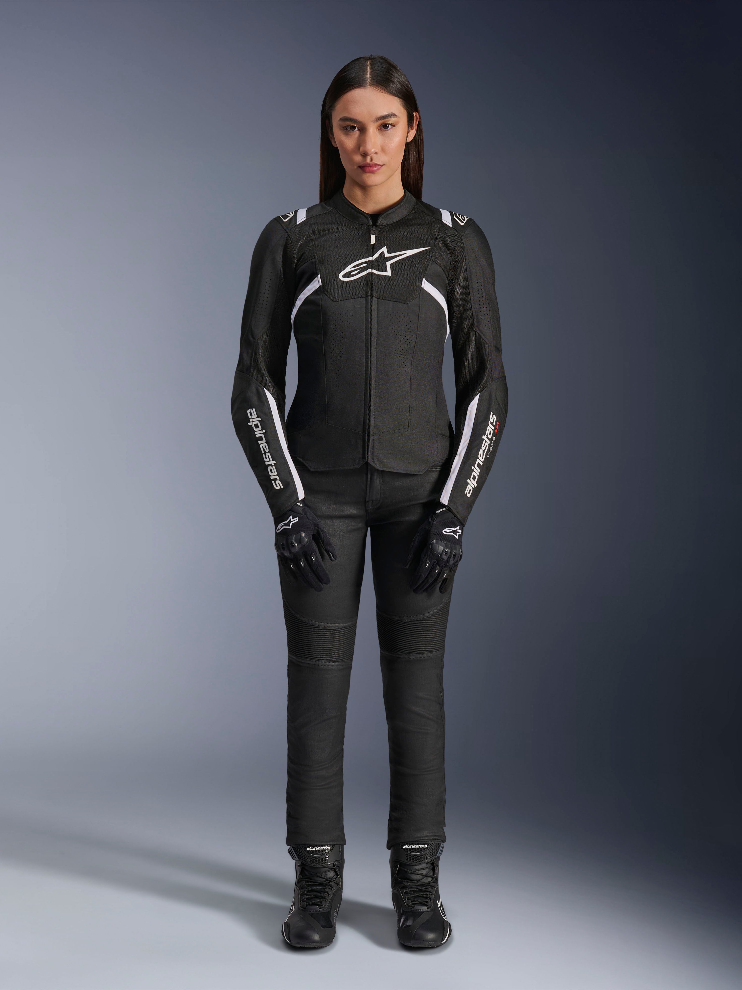 Alpinestars Stella T-Sps Air V2 Jacket, damska kurtka motocyklowa, czarno-biała, z panelami z siatki i białymi akcentami, noszona z czarnymi spodniami, rękawicami i butami, sportowy krój do jazdy miejskiej