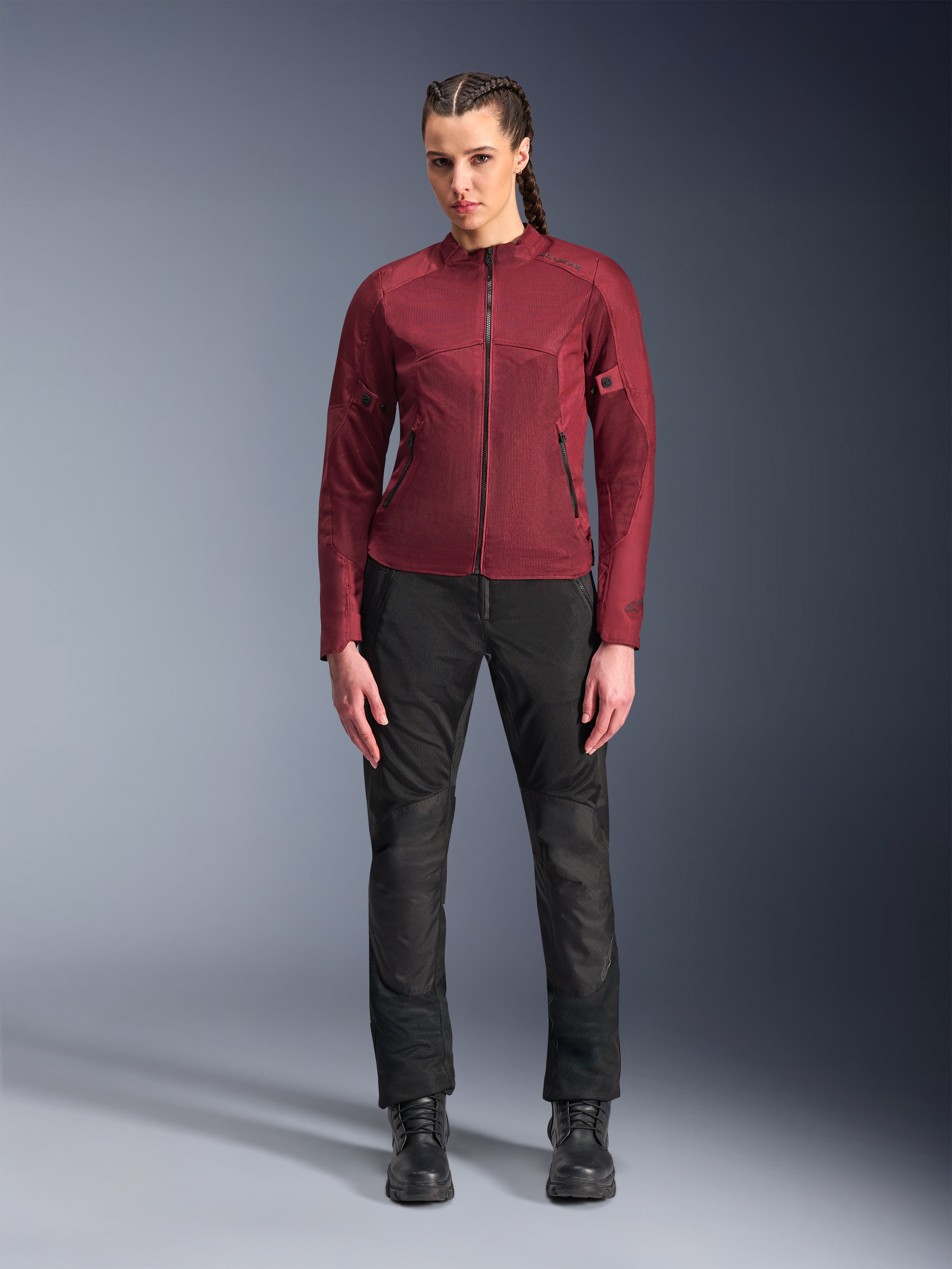Damska kurtka Alpinestars Stella C-1 Air, bordowa tekstylna kurtka motocyklowa, z panelami z siatki zapewniającymi wentylację i kieszeniami zapinanymi na zamek, noszona przez modelkę z czarnymi spodniami motocyklowymi i butami, nowoczesna odzież miejska dla kobiet