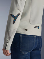 Damska kurtka Alpinestars Stella Circal-1 Air w kolorze Metal Gray i Methyl Blue, zbliżenie na tył i detal rękawa z siatkowymi panelami wentylacyjnymi, neonowo-niebieskie akcenty na łokciu i w talii, pasek do regulacji, noszona z ciemnoniebieskimi jeansami.
