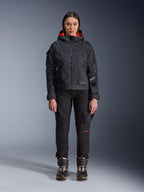 Modelka w kurtce Alpinestars Molly Air Jacket w kolorze Black i Fluo Coral, o designie inspirowanym stylem użytkowym z kapturem i koralową podszewką, w zestawieniu z czarnymi spodniami i butami motocyklowymi, współczesna miejska odzież motocyklowa