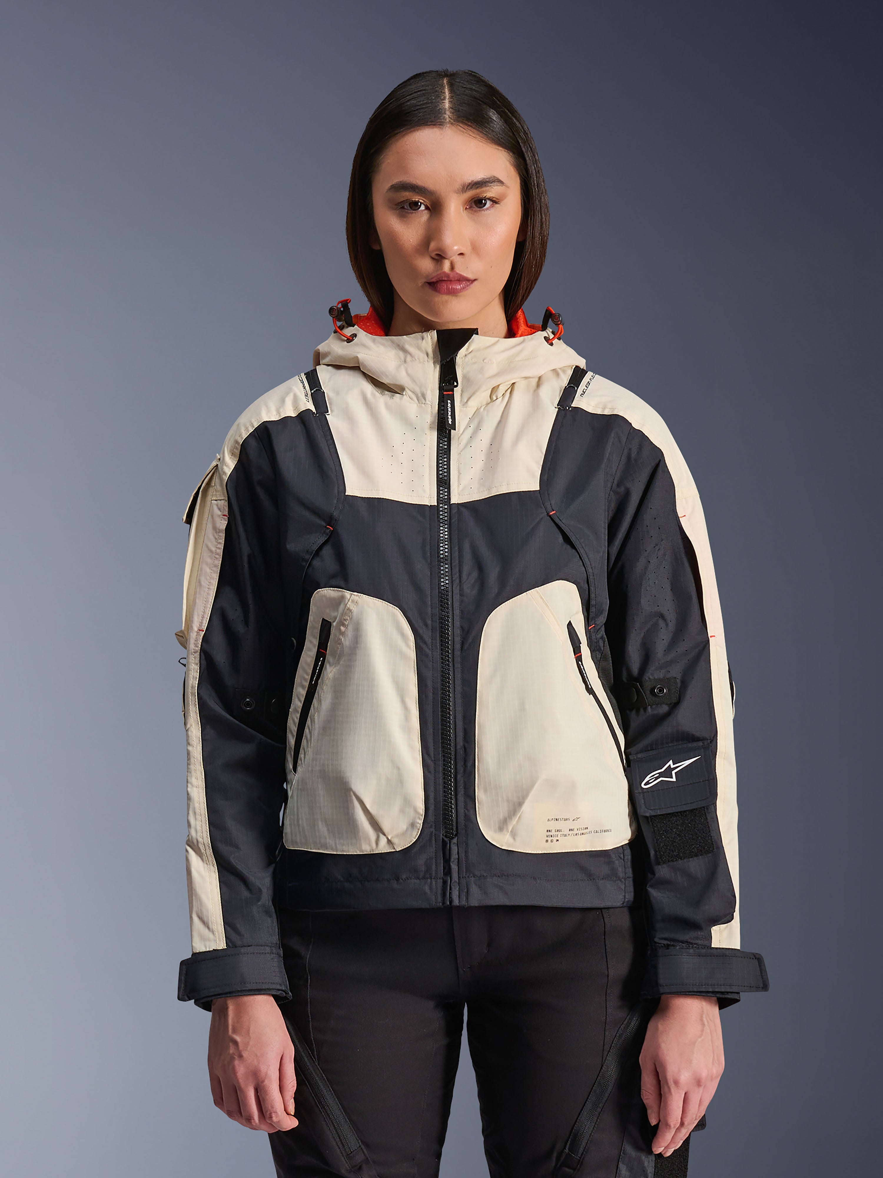 Alpinestars Molly Air Jacket, damska miejska kurtka motocyklowa, Black Almond, widok z przodu na modelce, kremowe i czarne panele ripstop, kaptur z pomarańczową podszewką, przednie zapięcie na zamek, duże kieszenie użytkowe, współczesna odzież motocyklowa inspirowana stylem streetwear