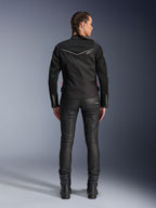 Alpinestars Stella T-Dyno Air Jacket, widok z tyłu, czarna damska kurtka motocyklowa z białymi lamówkami i małym logo gwiazdy, noszona z czarnymi spodniami technicznymi i butami motocyklowymi, dopasowany fason motocyklowy do miejskiej jazdy szosowej