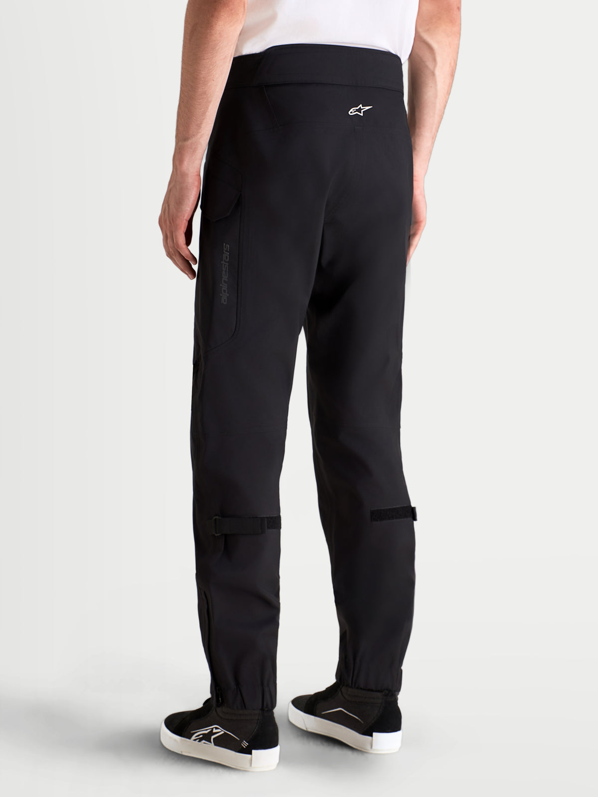 Alpinestars Juggernaut V2 Drystar spodnie motocyklowe miejskie męskie, czarne, widok z tyłu na model w pasującym sprzęcie i butach, z wysokim pasem i kieszeniami typu cargo