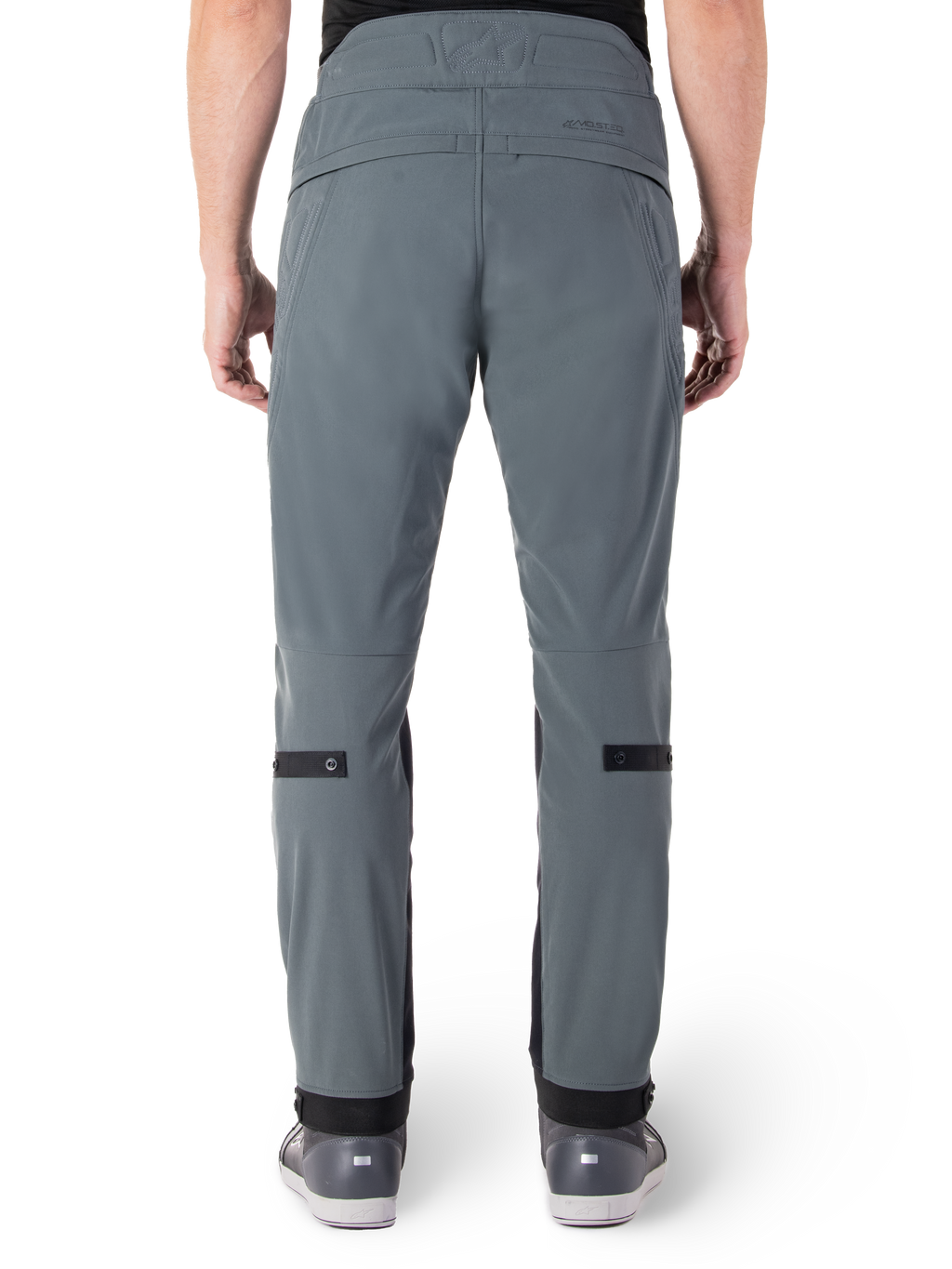 Alpinestars Alden Pants, Urban Gray, widok z tyłu męskich miejskich spodni motocyklowych, wąski krój poniżej kolana z czarnymi paskami do regulacji na łydkach, wysoki stan z napisem MO.ST.EQ. na tylnym karczku, noszone z szarymi butami do jazdy
