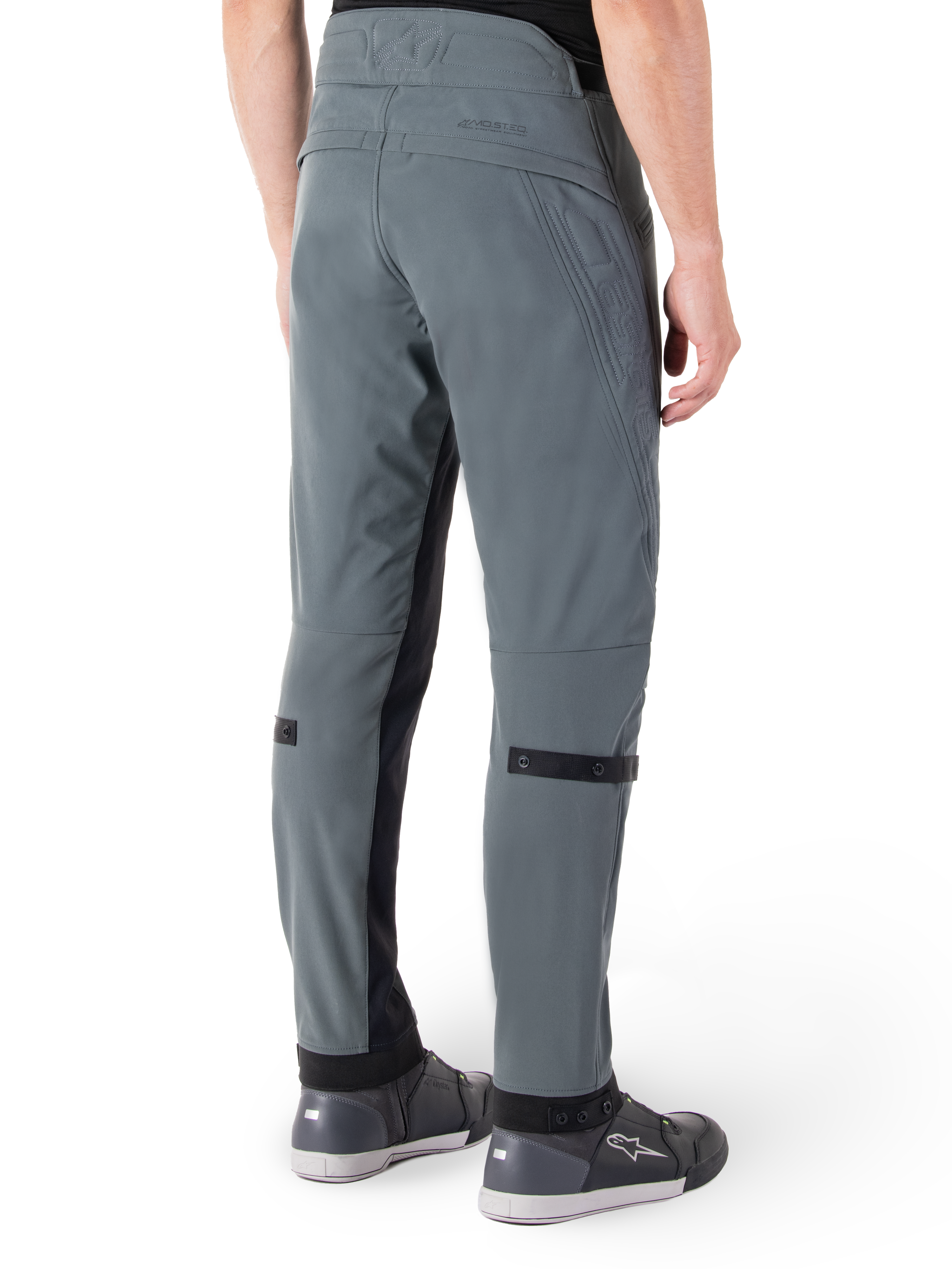 Spodnie Alpinestars Alden, Urban Gray, widok z boku od tyłu, techniczne spodnie motocyklowe inspirowane streetwearem z pikowanymi detalami w talii i czarnymi paskami na łydkach, szare buty motocyklowe, nowoczesna miejska odzież motocyklowa