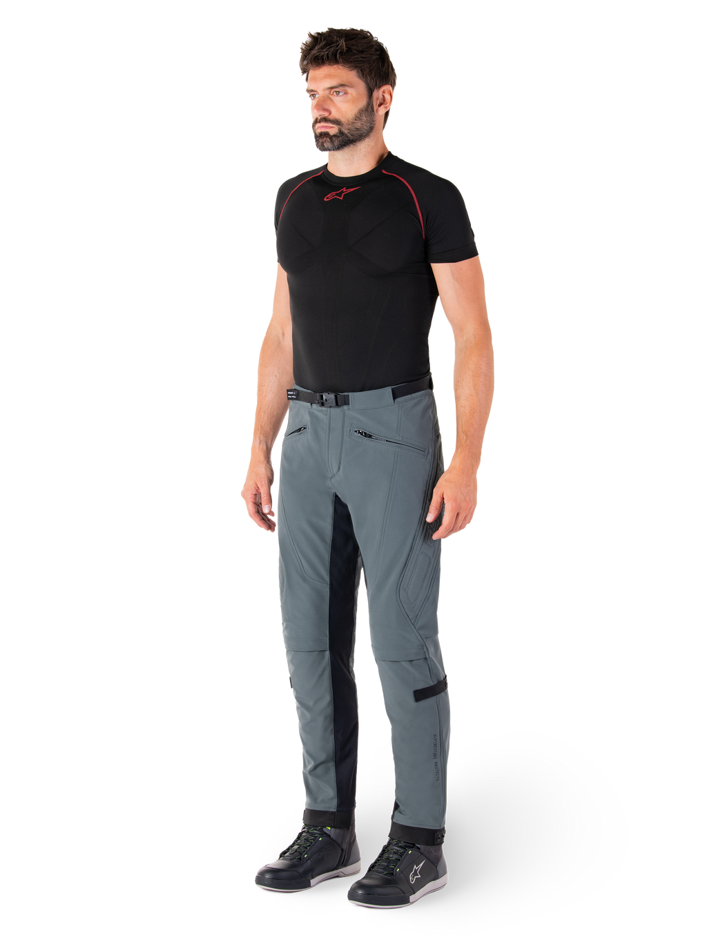 Spodnie Alpinestars Alden, techniczne spodnie motocyklowe w kolorze Urban Gray, wyposażone w pikowane panele boczne i czarny elastyczny materiał po wewnętrznej stronie nogawek, zestawione z czarną warstwą bazową i butami motocyklowymi, miejska odzież motocyklowa inspirowana streetwearem