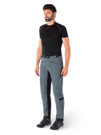 Spodnie Alpinestars Alden, techniczne spodnie motocyklowe w kolorze Urban Gray, wyposażone w pikowane panele boczne i czarny elastyczny materiał po wewnętrznej stronie nogawek, zestawione z czarną warstwą bazową i butami motocyklowymi, miejska odzież motocyklowa inspirowana streetwearem