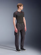 Alpinestars Flex-AST Cargo Pants, czarne, miejskie spodnie motocyklowe z kieszeniami cargo i elastycznymi mankietami, prezentowane przez modela w czarnej koszulce termoaktywnej z krótkim rękawem i sneakersach, nowoczesny zwężany krój