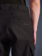 Alpinestars Flex-AST Cargo Pants, miejskie spodnie motocyklowe, czarne, zbliżenie na tył i bok z widoczną tylną kieszenią z logo Alpinestars, klapą bocznej kieszeni cargo i wytrzymałą konstrukcją z elastycznego materiału