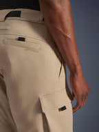 Alpinestars Flex-AST Cargo Pants - Short, jasnobeżowe, zbliżenie z boku pokazujące kieszeń cargo z czarnym uchwytem i haftowane logo na tylnej kieszeni, wytrzymały materiał tekstylny, miejska odzież motocyklowa.