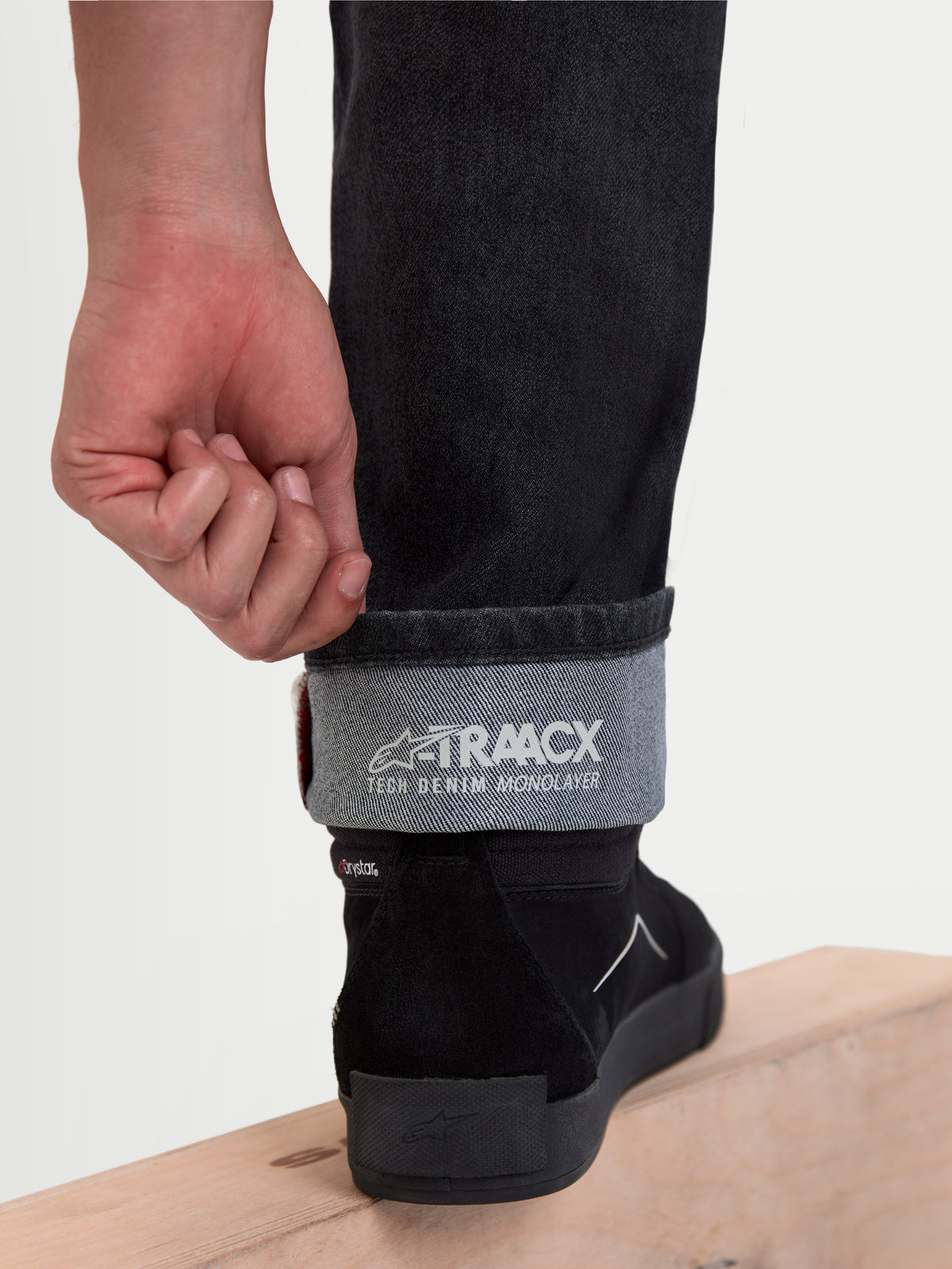 Alpinestars Flex-AST 8 Denim Pants, motorcycle urban riding jeans in Used Black, close-up view of the cuffed leg showing the A-TRAACX single-layer technical denim construction and interior branding