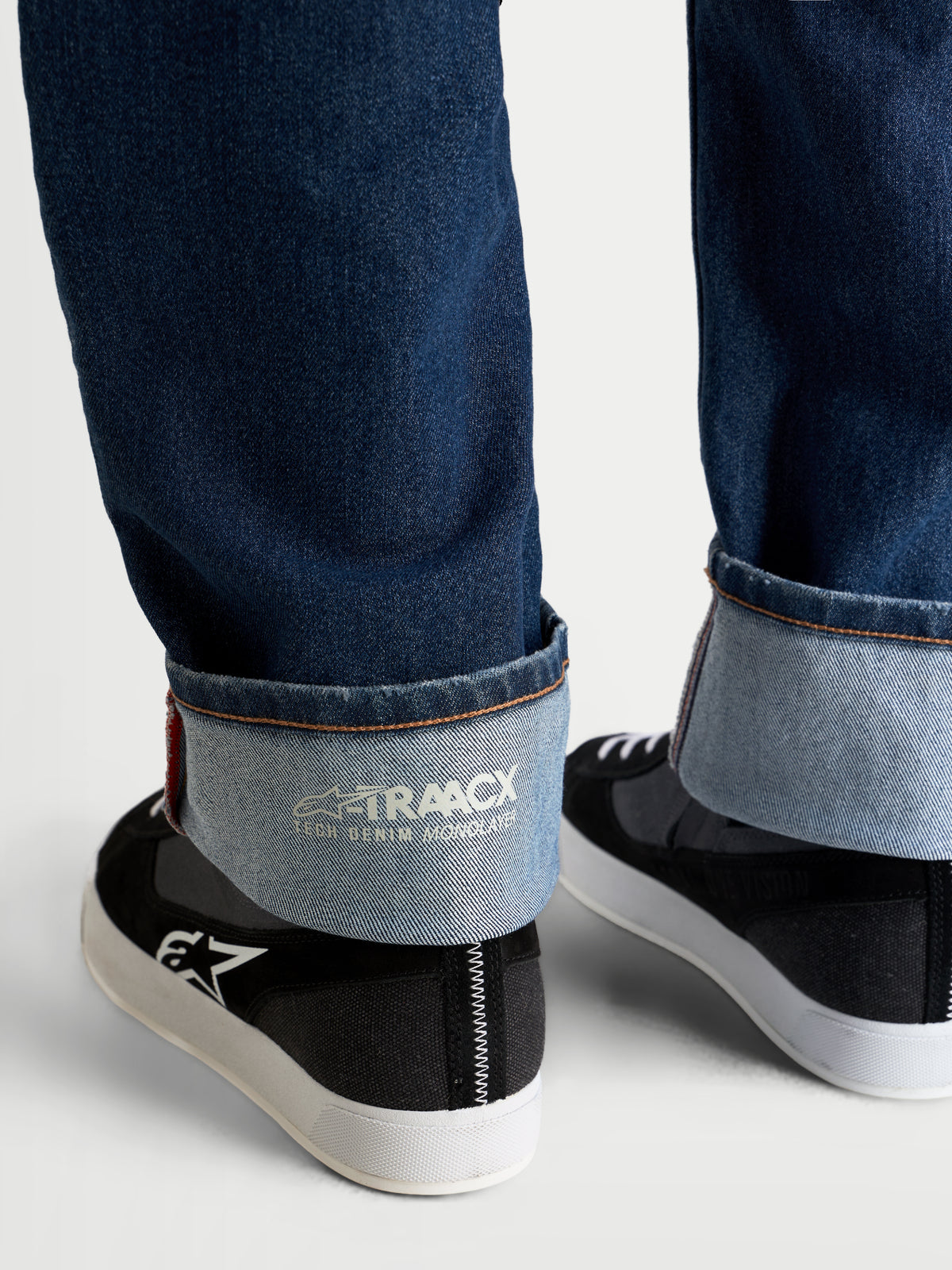 Alpinestars Flex Ast 8 Denim Spodnie motocyklowe jeansy, niebieskie, zbliżenie na wywinięty brzeg nogawki z widocznym brandingiem A-TRAACX i wykończeniem typu selvedge